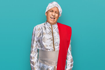 Senior hispanic man wearing tradition sherwani saree clothes winking looking at the camera with...