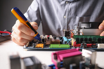 Technician repairing electronic circuit board at table, closeup
