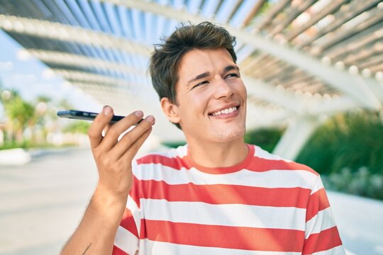 Young caucasian man smiling happy listening audio message using smartphone at the city.