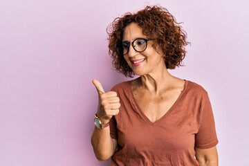 Beautiful middle age mature woman wearing casual clothes and glasses smiling with happy face...
