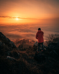 man stay on a mountain top enjoying sunset over the clouds