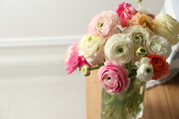 Beautiful ranunculus flowers in vase on table indoors, closeup. Space for text