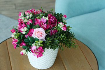 modern bedroom closeup fragment with flowers in vase, sofa and pillows on background