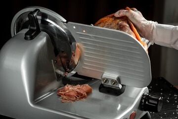 Slicing Hamon on cutting machine. Iberian ham cutter on black background