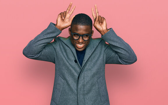 Young african american man wearing business clothes and glasses posing funny and crazy with fingers on head as bunny ears, smiling cheerful
