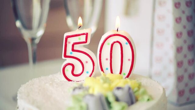 Birthday candle as number fifty 50 on top of sweet cake on the table, 50th birthday, toned video
