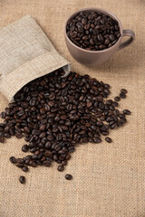 Bunch of medium roasted coffee beans out of sackcloth on marble surface