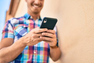 Young caucasian man smiling happy using smartphone at the city.