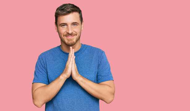 Handsome caucasian man wearing casual clothes praying with hands together asking for forgiveness smiling confident.