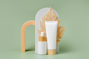 Cream tube and dropper mockup with leaf and geometrical forms on green background. Natural skincare...