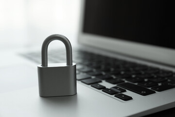 Metal lock and laptop on light background, closeup. Cyber security concept