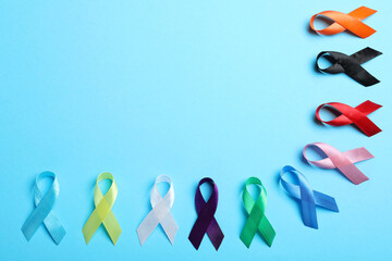 Colorful ribbons on light blue background, flat lay with space for text. World Cancer Day