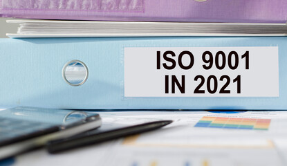 ISO 9001 in 2021 text written on folder with documents and calculator.
