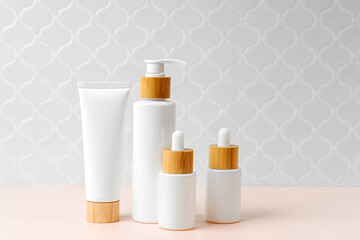 Pump bottle, cream tube, and dropper on table in bathroom. Cosmetic container mock-ups. Background for branding and packaging presentation. Natural skincare beauty product concept.