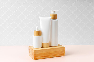 Pump bottle, cream tube, and dropper on table in bathroom. Cosmetic container mock-ups. Background for branding and packaging presentation. Natural skincare beauty product concept.