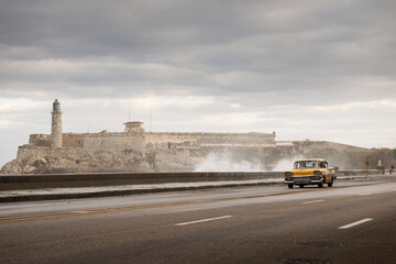 Old car on Malecon street of Havana with storm clouds in background. Cuba