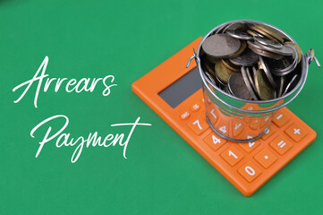 Calculator and coins over green background written with ARREARS PAYMENT.