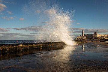 Big waves on Malecon streets during sunrise with storm clouds in background. Havana, Cuba