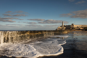 Big waves on Malecon streets during sunrise with storm clouds in background. Havana, Cuba