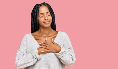 Beautiful hispanic woman wearing casual clothes smiling with hands on chest with closed eyes and grateful gesture on face. health concept.