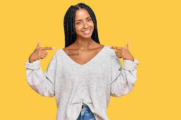 Beautiful hispanic woman wearing casual clothes looking confident with smile on face, pointing...