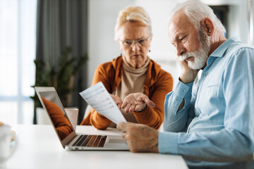 Frustrated senior couple sitting at home and checking their home finance