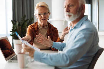 Frustrated senior couple arguing about their home finances at home