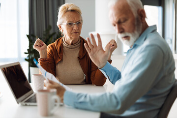 Frustrated senior couple arguing about their home finances at home