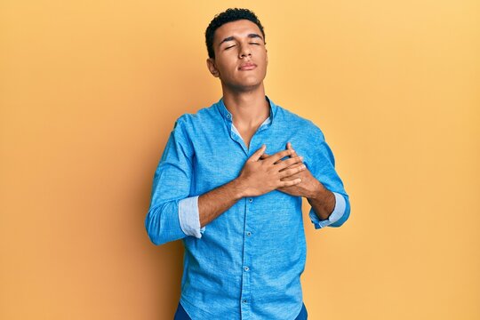 Young arab man wearing casual clothes smiling with hands on chest with closed eyes and grateful gesture on face. health concept.