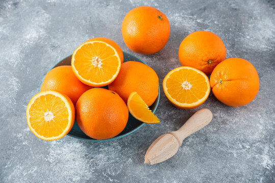 A bowl full of sliced and whole juicy orange fruits with wooden reamer © azerbaijan-stockers