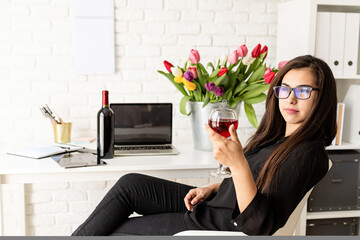 Young confident business woman florist drinking wine, celebrating at the office