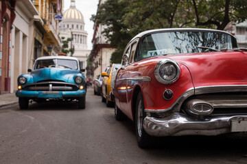 Plakat Old car on streets of Havana with colourful buildings in background. Cuba