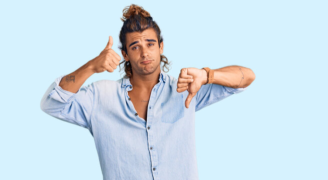 Young hispanic man wearing summer style doing thumbs up and down, disagreement and agreement expression. crazy conflict