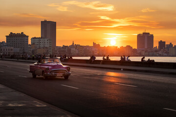 Old car on Malecon street of Havana with colourful sunset in background. Cuba