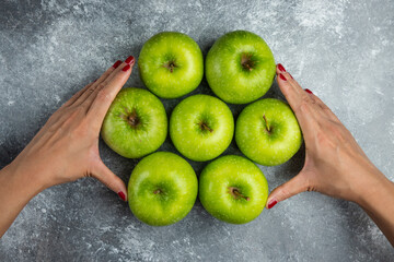Woman hand holding bunch of apples on marble background