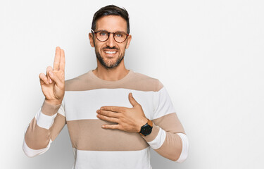 Handsome man with beard wearing casual clothes and glasses smiling swearing with hand on chest and...