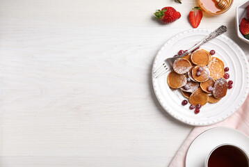 Delicious mini pancakes cereal with cranberries served on white wooden table, flat lay. Space for text