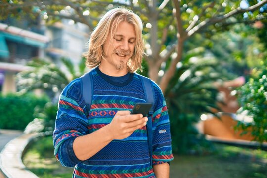 Young scandinavian student man smiling happy using smartphone at the park.