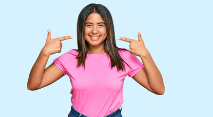 Obraz na płótnie Canvas Young latin girl wearing casual clothes smiling cheerful showing and pointing with fingers teeth and mouth. dental health concept.