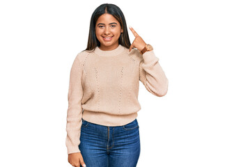 Young latin girl wearing wool winter sweater smiling doing phone gesture with hand and fingers like talking on the telephone. communicating concepts.