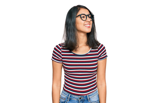 Beautiful asian young woman wearing casual clothes and glasses looking away to side with smile on face, natural expression. laughing confident.