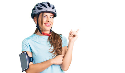 Beautiful caucasian young woman wearing bike helmet smiling happy pointing with hand and finger to the side