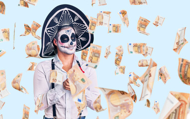 Man wearing day of the dead costume over background with hands together and crossed fingers smiling relaxed and cheerful. success and optimistic