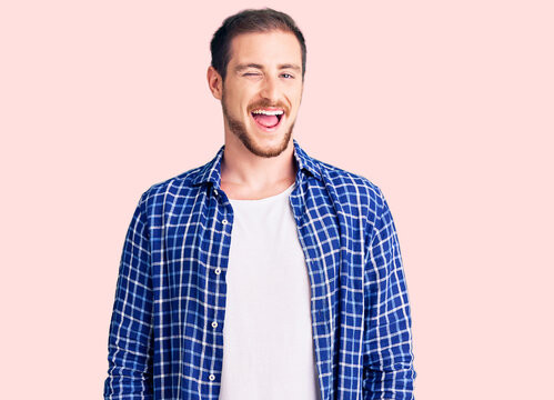Young handsome caucasian man wearing casual clothes winking looking at the camera with sexy expression, cheerful and happy face.
