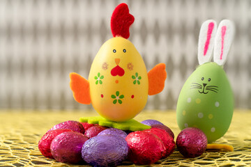 décoration de pâques un lapin et une petite poule de pâques devant un fond gris avec des losange