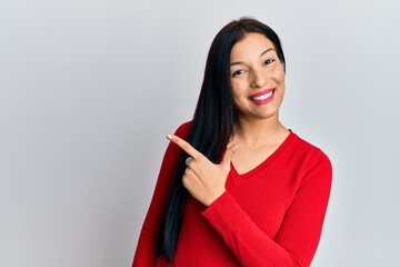 Young latin woman wearing casual clothes smiling cheerful pointing with hand and finger up to the side
