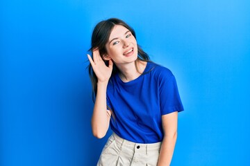 Young beautiful caucasian girl wearing casual clothes smiling with hand over ear listening and hearing to rumor or gossip. deafness concept.