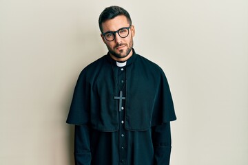 Obraz premium Young hispanic man wearing priest uniform standing over white background skeptic and nervous, frowning upset because of problem. negative person.