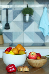 fruit in bowl still life with pot plant, paprika and croissant on the table closeup photo on blue kitchen background