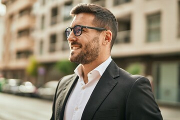 Young hispanic businessman smiling happy standing at the city.